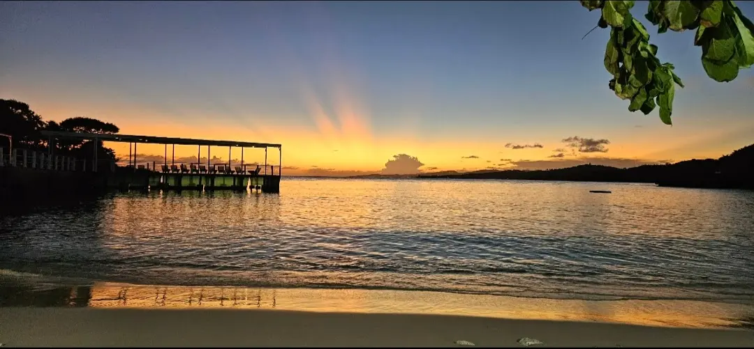 Sunset over Media Luna’s beach and waterfront restaurant dock, Roatán