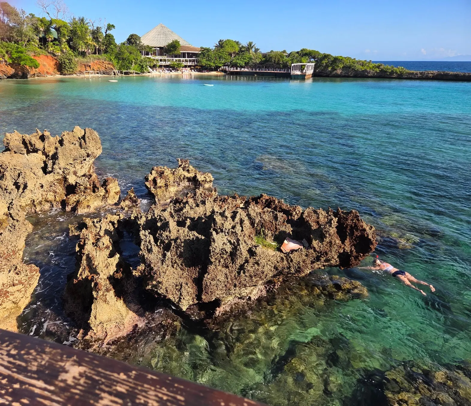 Snorkelers in turquoise water by the iron-shore rocks at Media Luna, Roatán