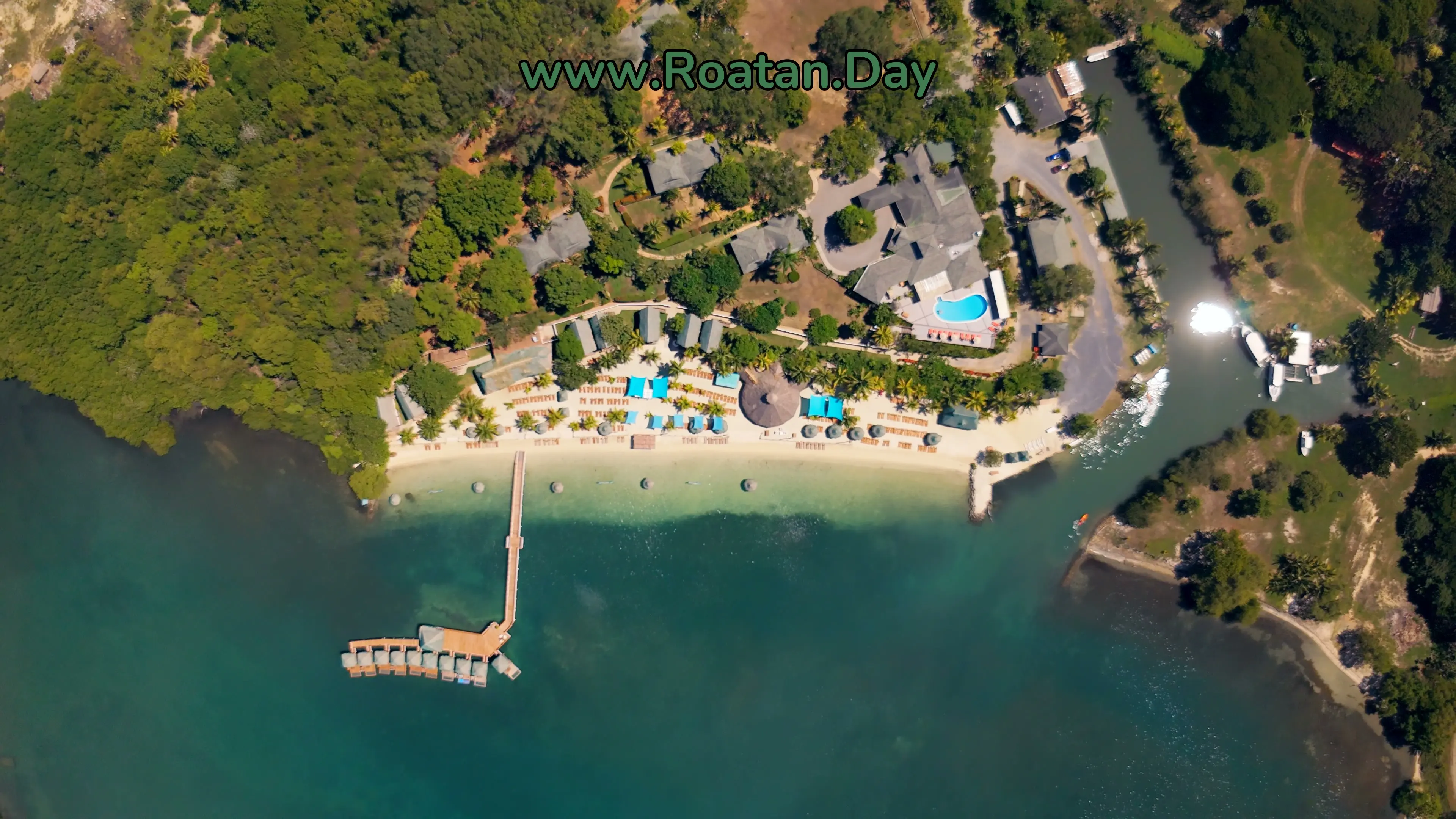 Turquoise Bay, Roatán, vue du drone à la verticale : les bungalows sur l'eau au bout du quai, la plage de sable blanc et la piscine
